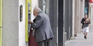 Un hombre mayor sacando dinero de un cajero.