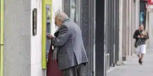Un hombre mayor sacando dinero de un cajero.